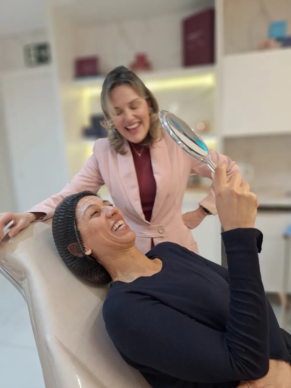 Dra. Silvia Nogueira e paciente sorrindo ao se ver no espelho