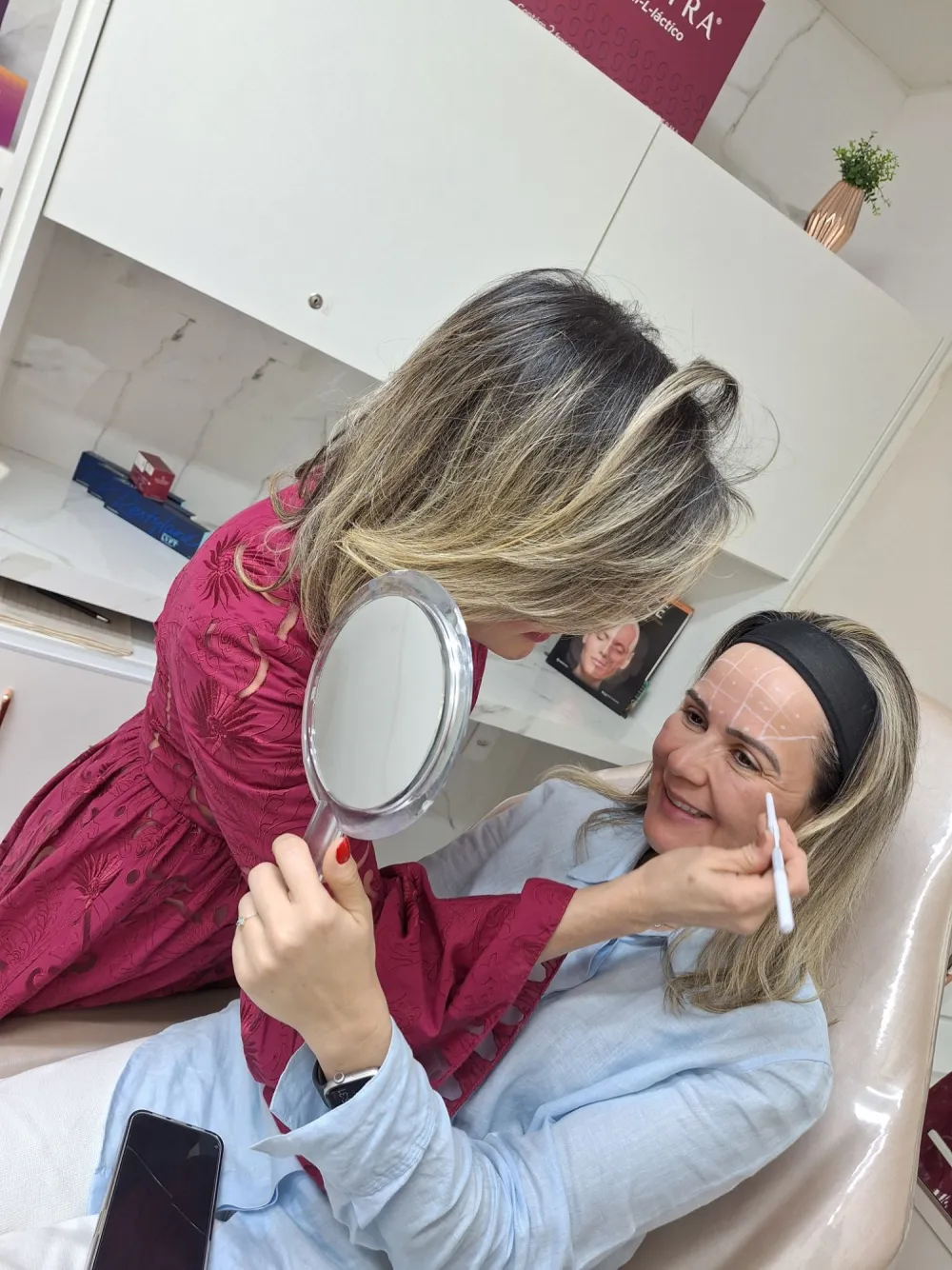 Dra. Silvia Nogueira marcando o rosto da paciente, que acompanha no espelho